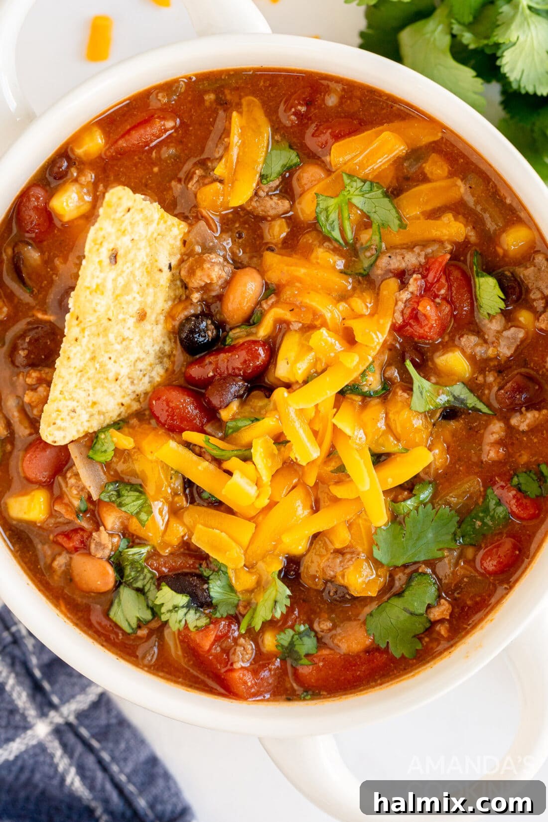 A single bowl of homemade taco soup, rich with ingredients, garnished with cheese and a spoon, inviting a taste.