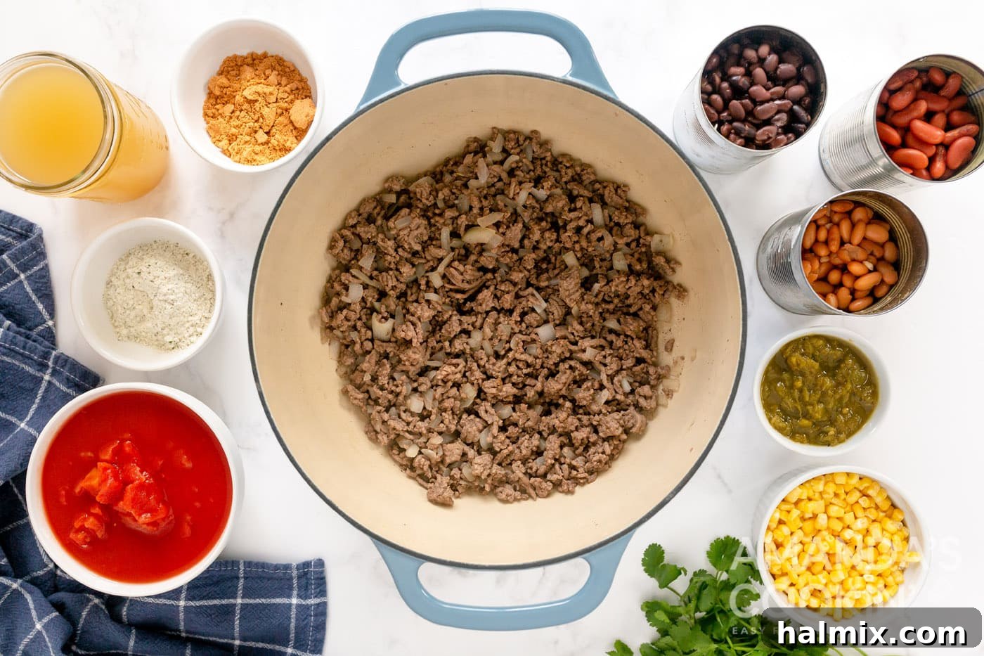 Perfectly browned ground beef and softened onions in a Dutch oven after draining excess fat, ready for the next ingredients.