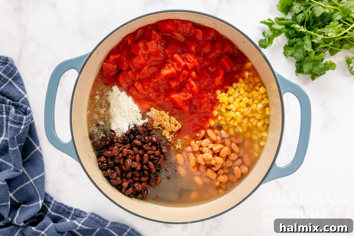 All the taco soup ingredients including chilis, beans, broth, seasoning, corn, and diced tomatoes combined in a pot before simmering.