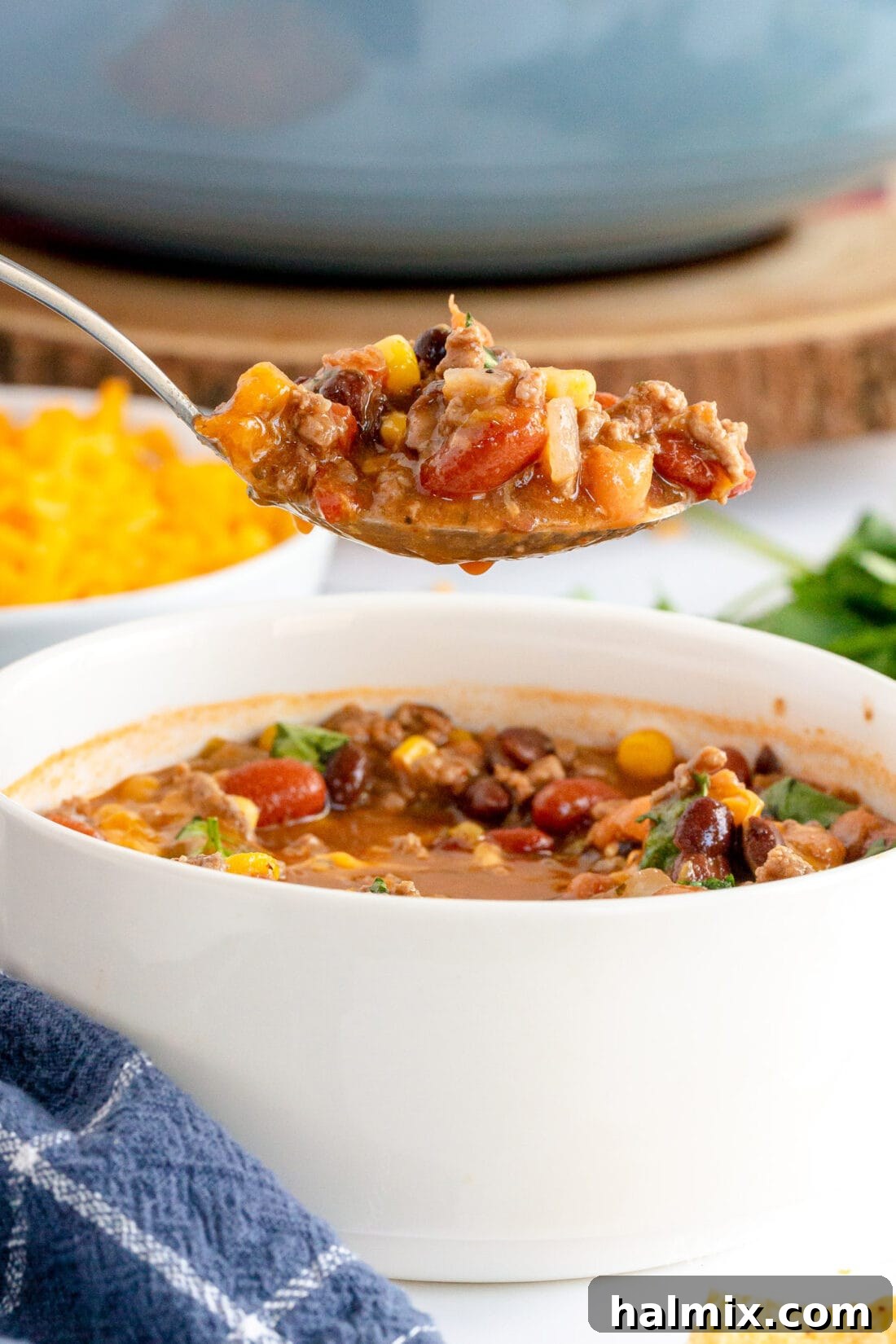 A close-up of a spoon lifting a scoop of rich, chunky taco soup, highlighting the textures of meat, beans, and corn.