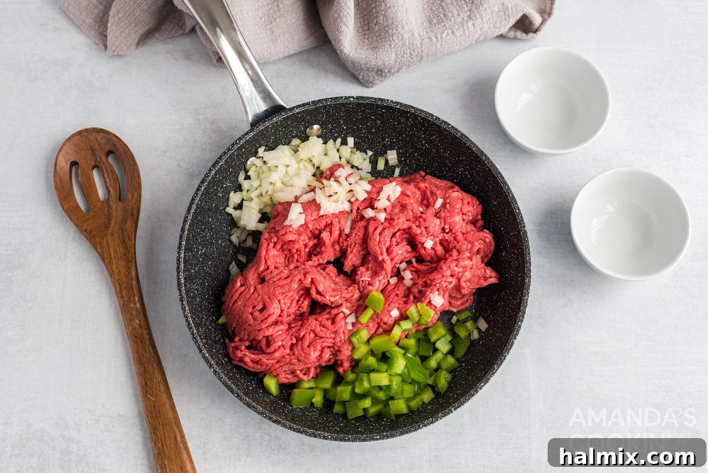 Messy Beef Bliss 5 Green pepper, onion, and ground beef sizzling in a skillet as they cook.