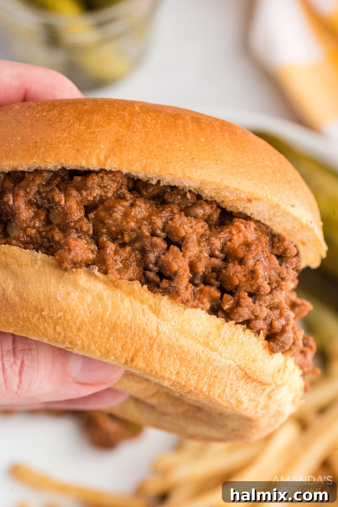 Messy Beef Bliss 9 A hand holding a perfectly assembled sloppy joe sandwich, showcasing its delicious filling.