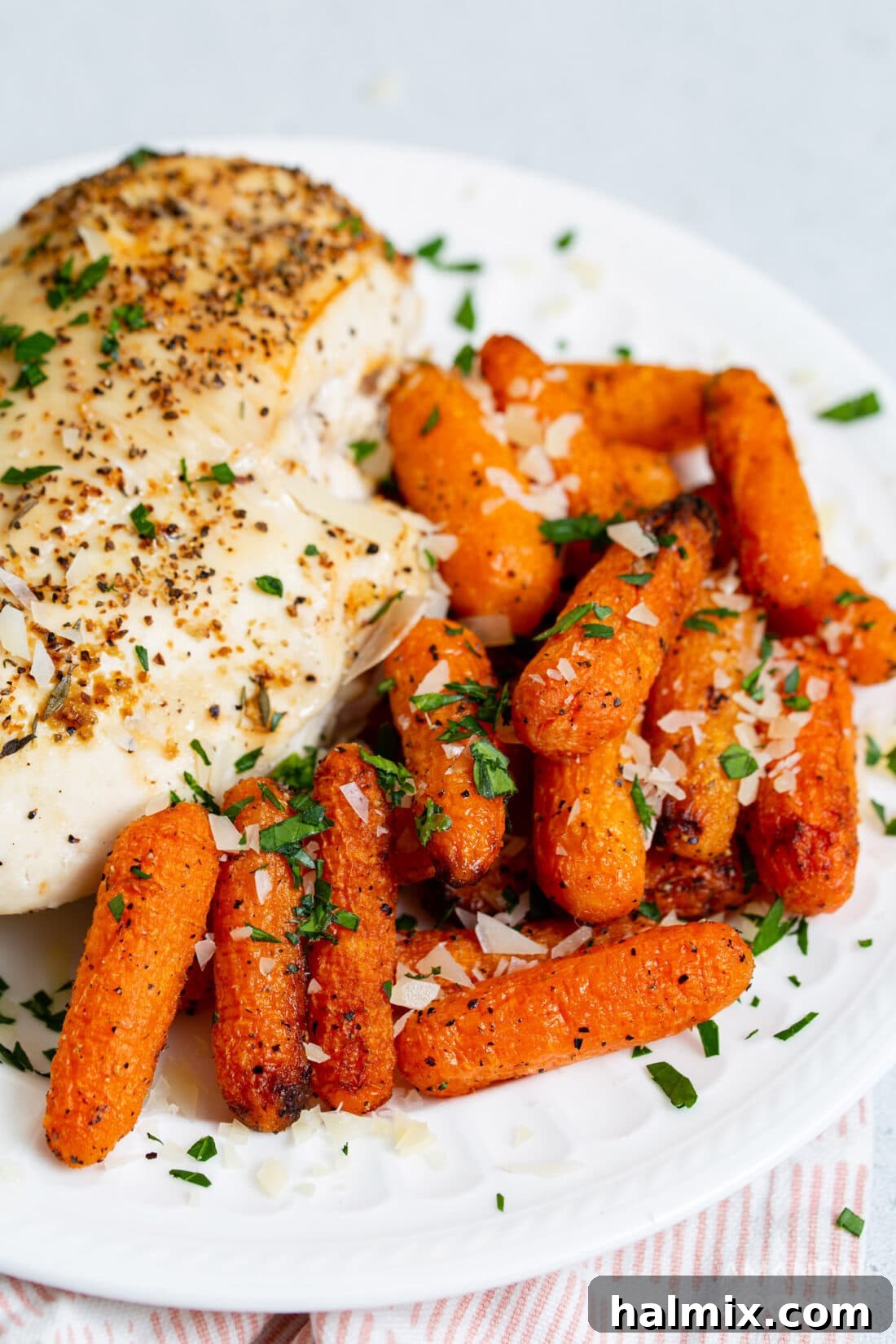 A plate featuring a serving of golden air fryer carrots alongside a perfectly cooked air fryer chicken breast.