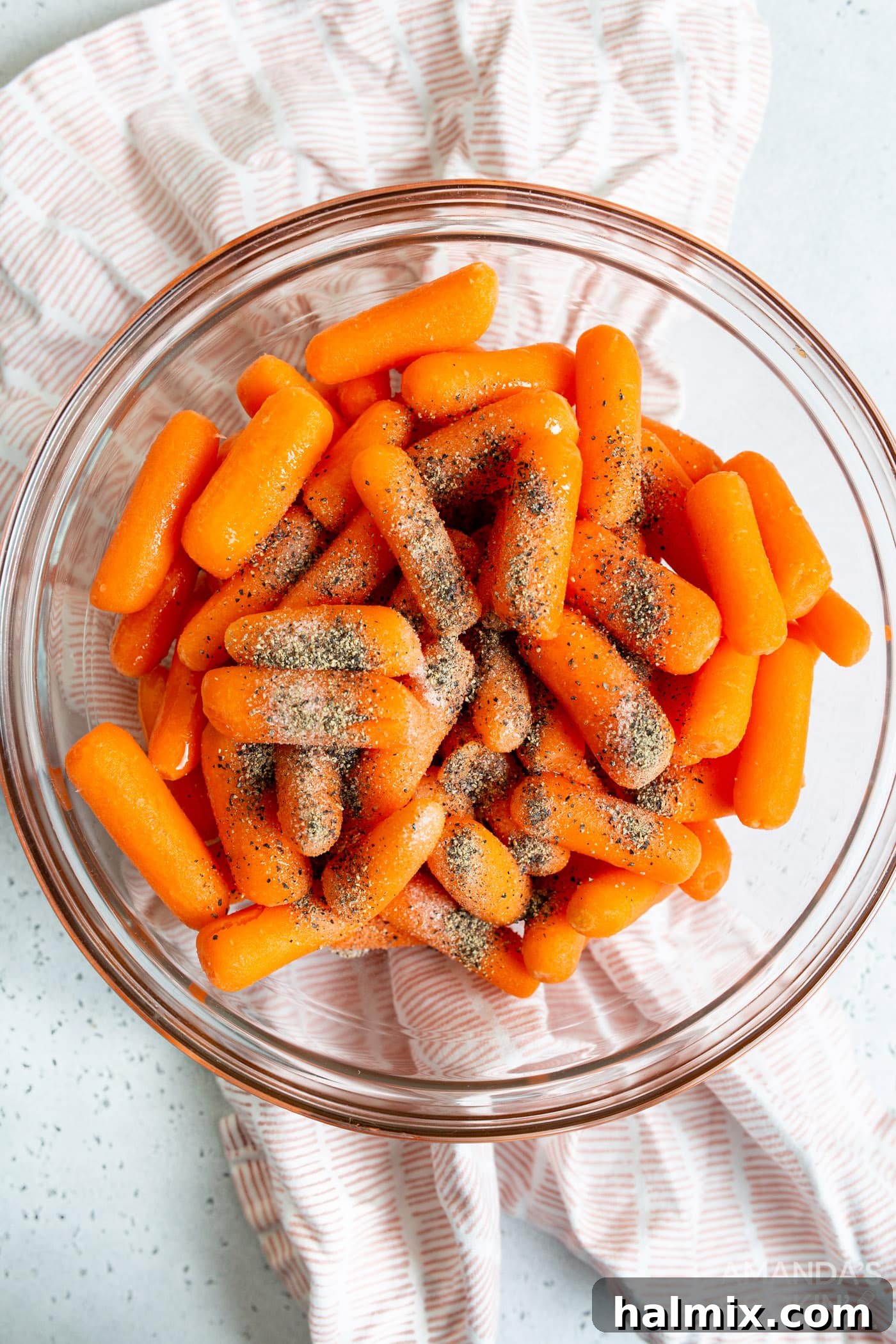 Carrots in a bowl, generously coated with oil and seasonings, ready for the air fryer.