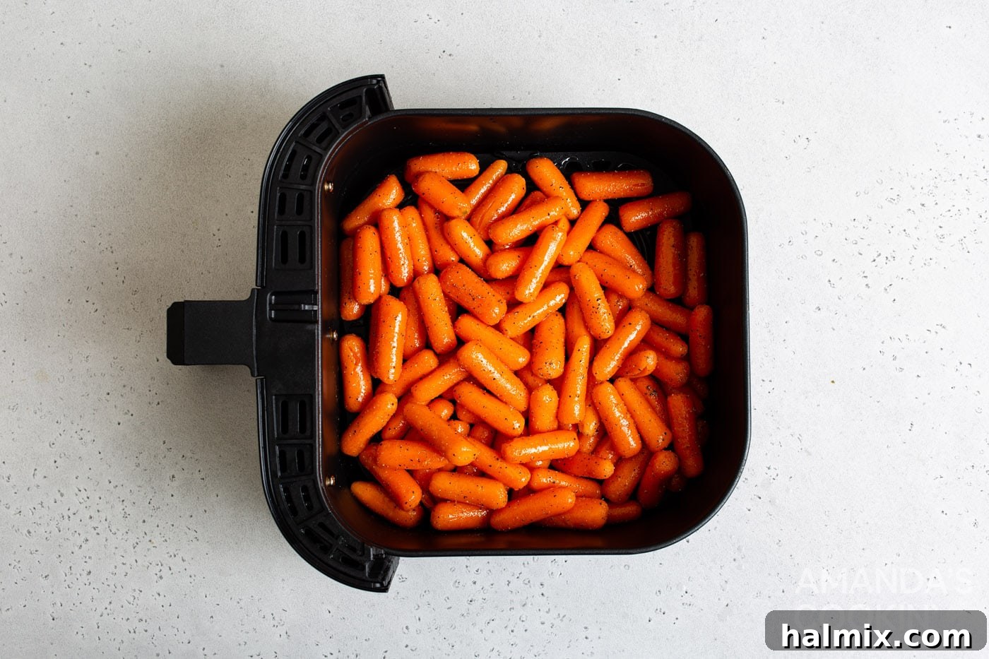 Seasoned carrots arranged inside an air fryer basket, ready for cooking.