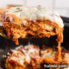 A spatula lifting a portion of cheesy crockpot lasagna from the slow cooker