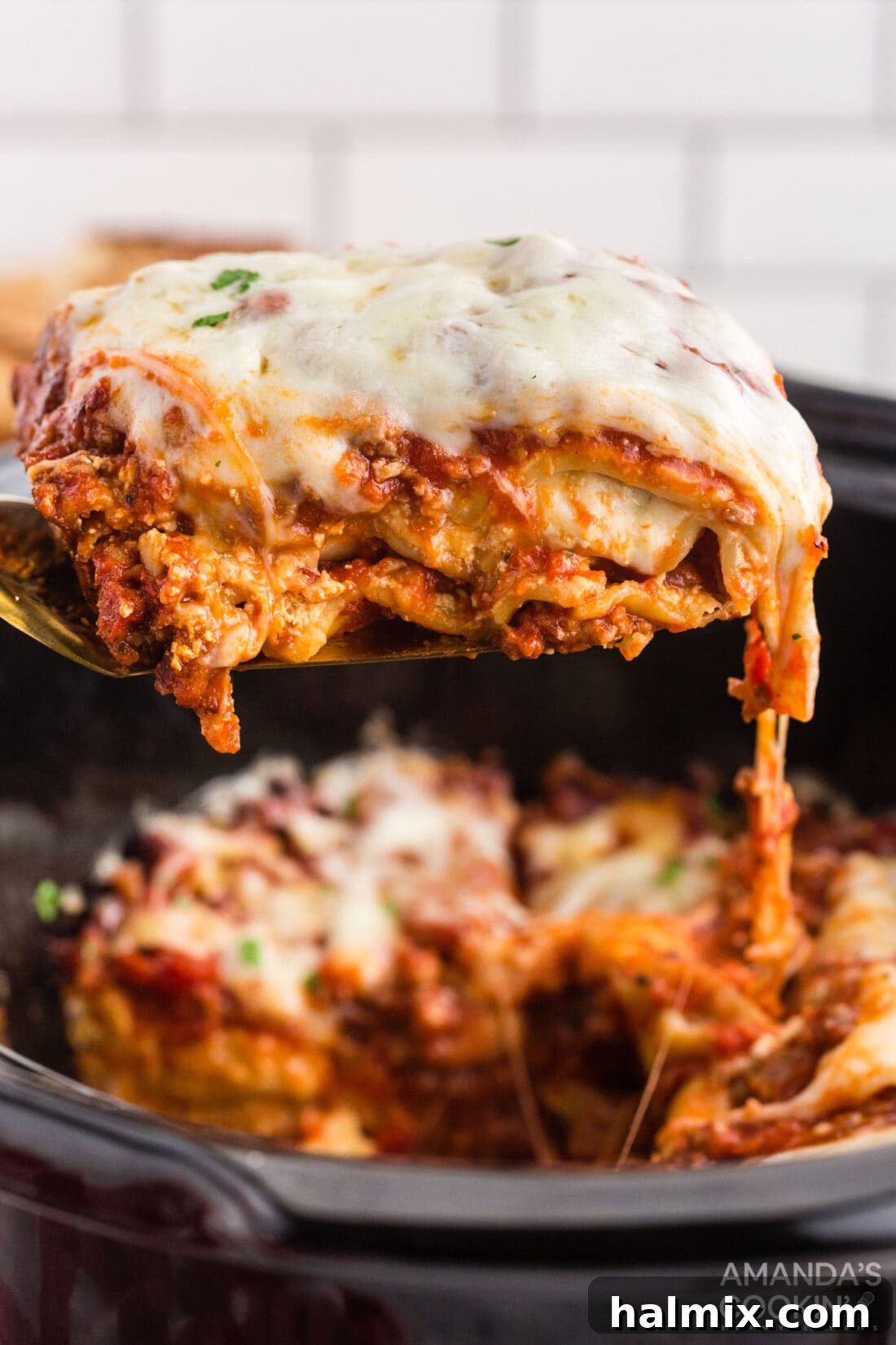 Effortless Slow Cooker Lasagna 3 A spatula lifting a generous portion of cheesy crockpot lasagna from the slow cooker
