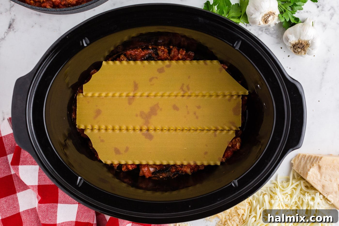 Effortless Slow Cooker Lasagna 8 First layer of lasagna noodles placed over meat sauce in a crockpot