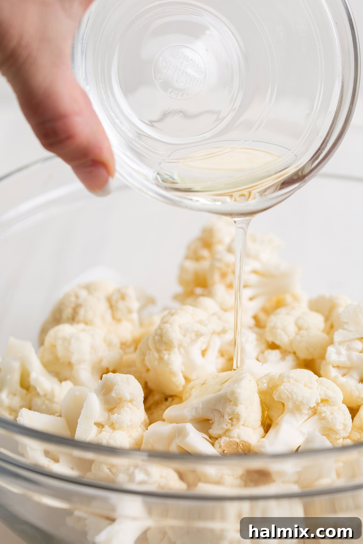 Golden Crispy Air Fryer Cauliflower 5 Oil being drizzled over cauliflower in a bowl