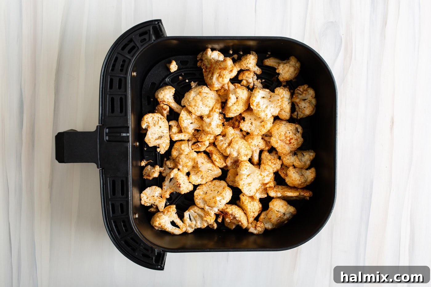 Golden Crispy Air Fryer Cauliflower 7 Seasoned cauliflower in an air fryer basket
