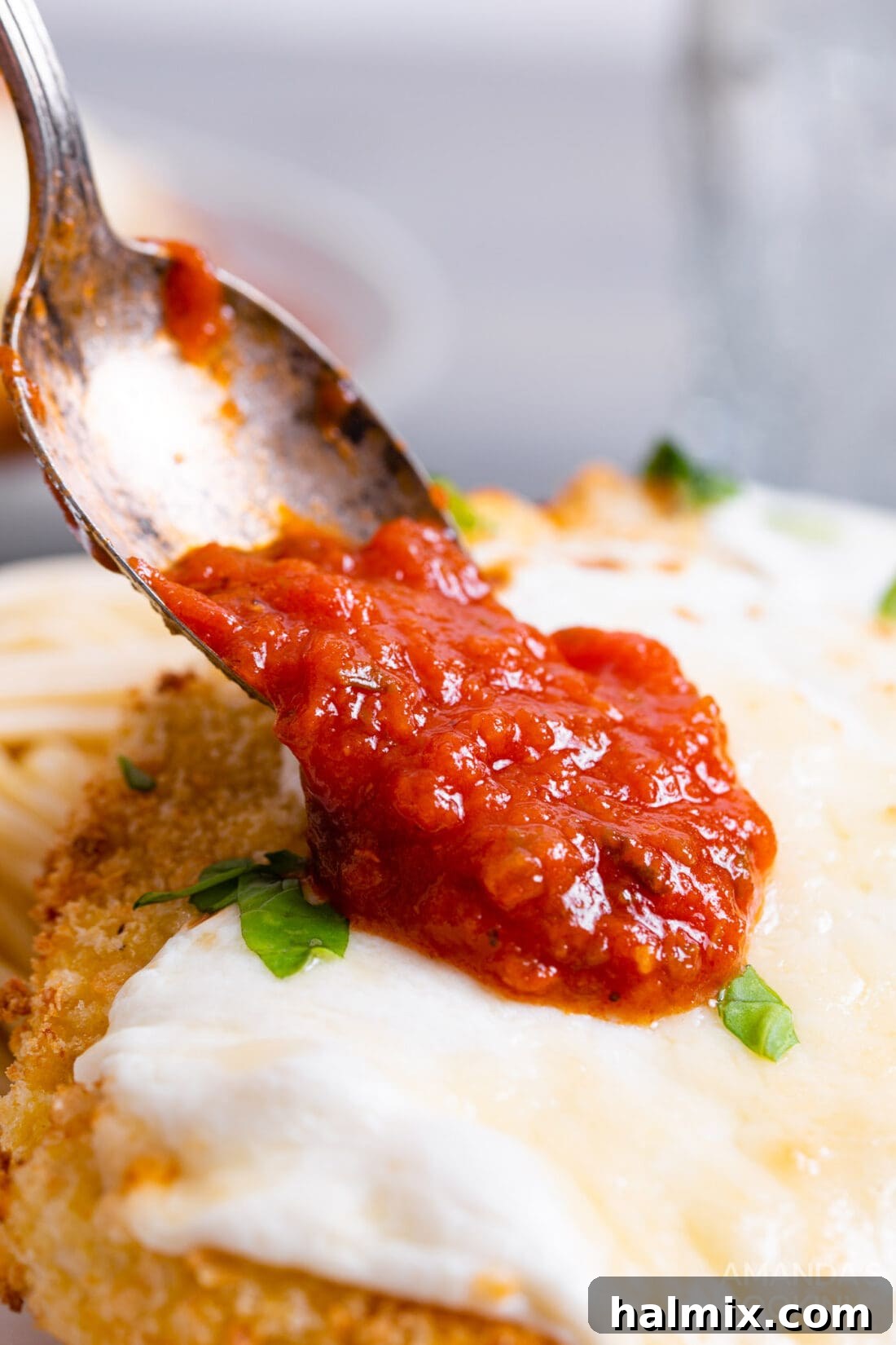 Crispy Air Fryer Chicken Parmesan 4 Spoonful of rich marinara sauce being added to a breaded chicken cutlet