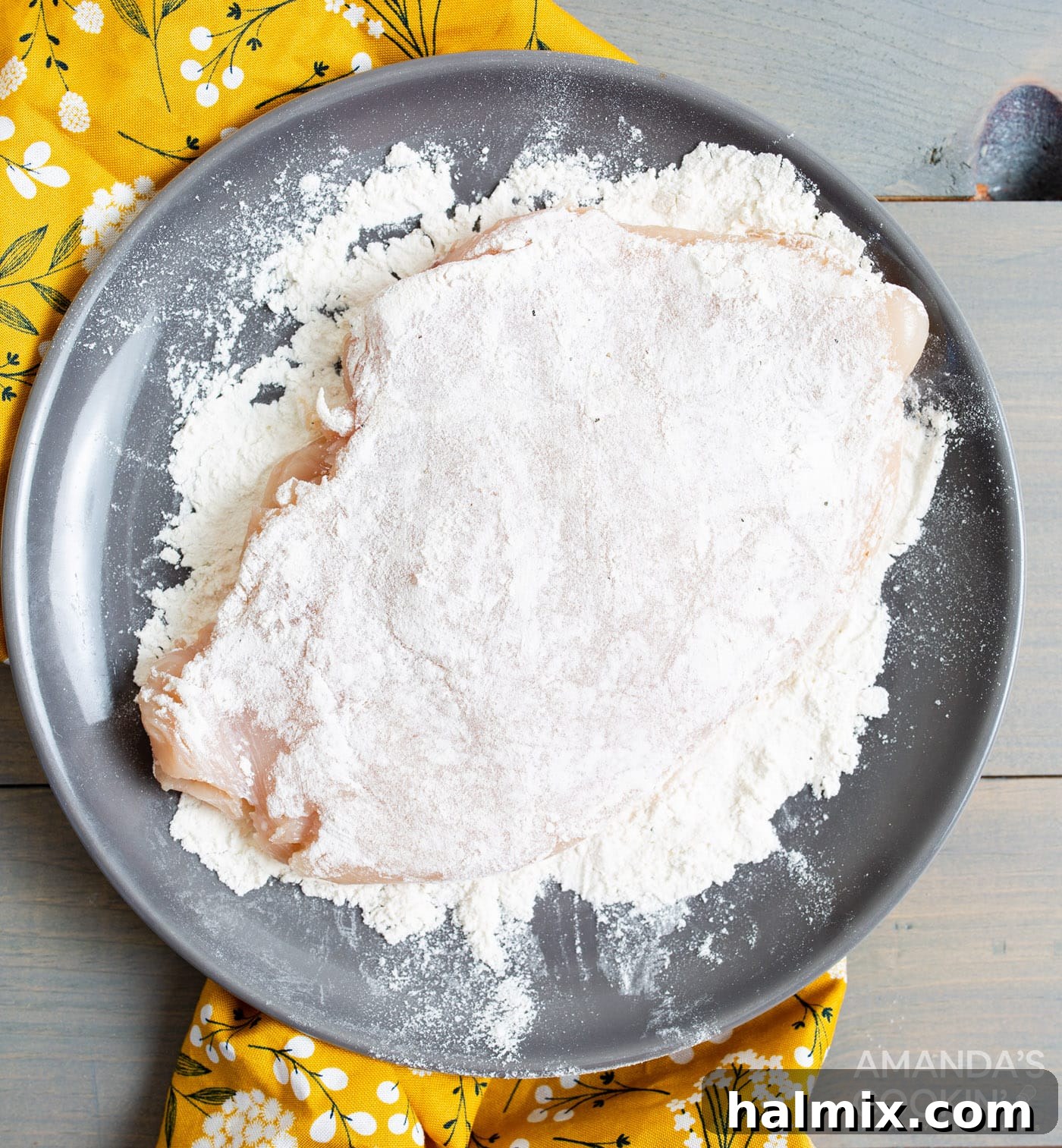 Chicken breast being coated in flour