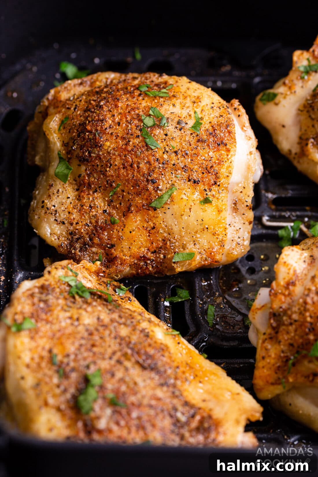 Golden Crispy Air Fryer Thighs 2 perfectly cooked chicken thighs with crispy skin in an air fryer basket, ready to serve