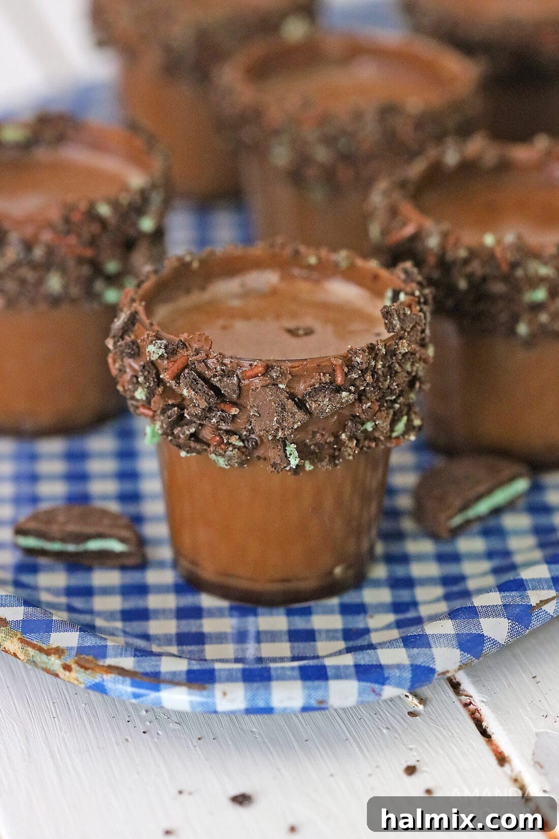 Two chocolate mint covered shot glasses on a blue tray, ready to be filled with the delicious dessert cocktail.