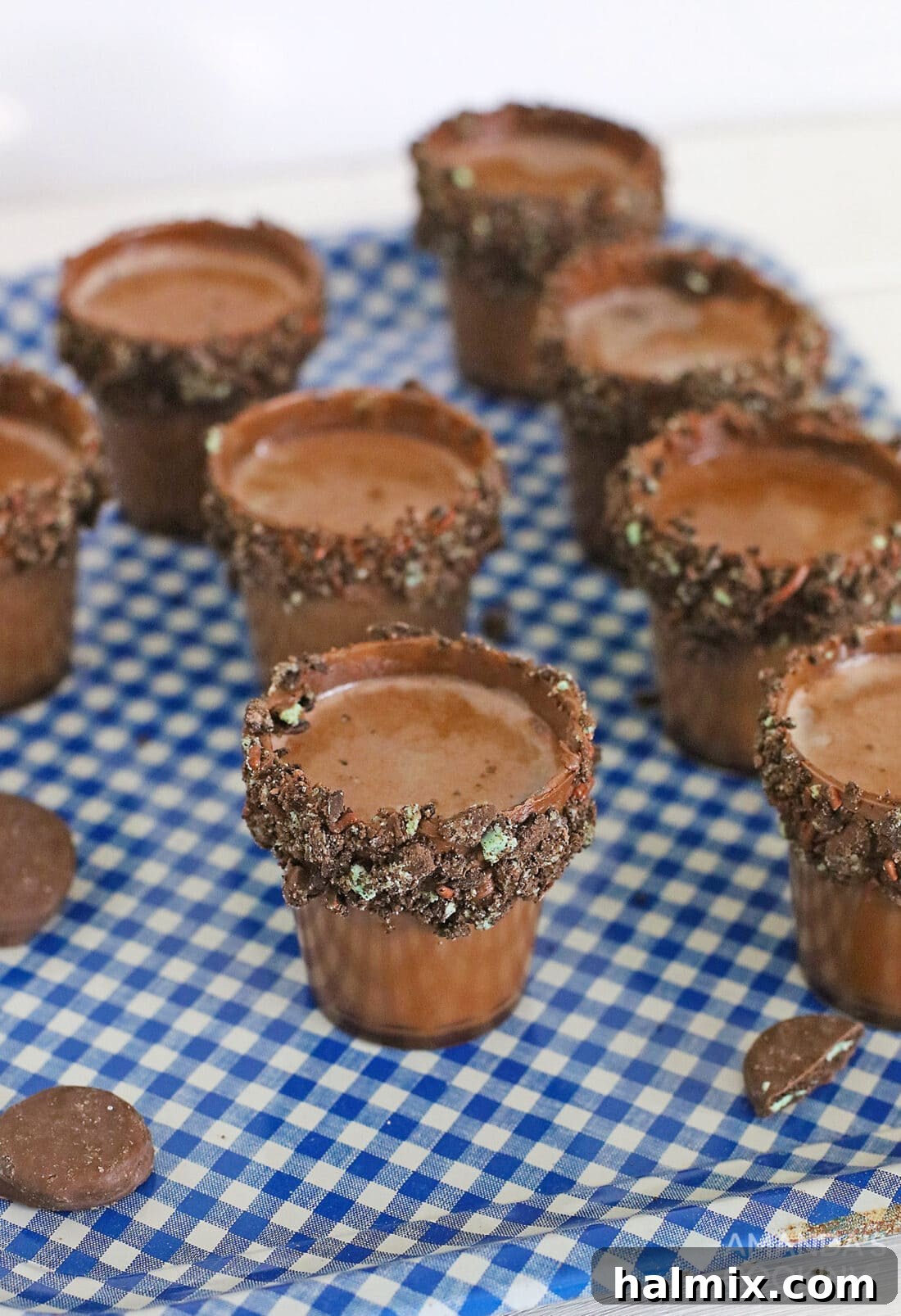 A tray filled with multiple Oreo Thin Mint Shooters, each beautifully decorated with cookie crumbs on the rim, ready for a party.