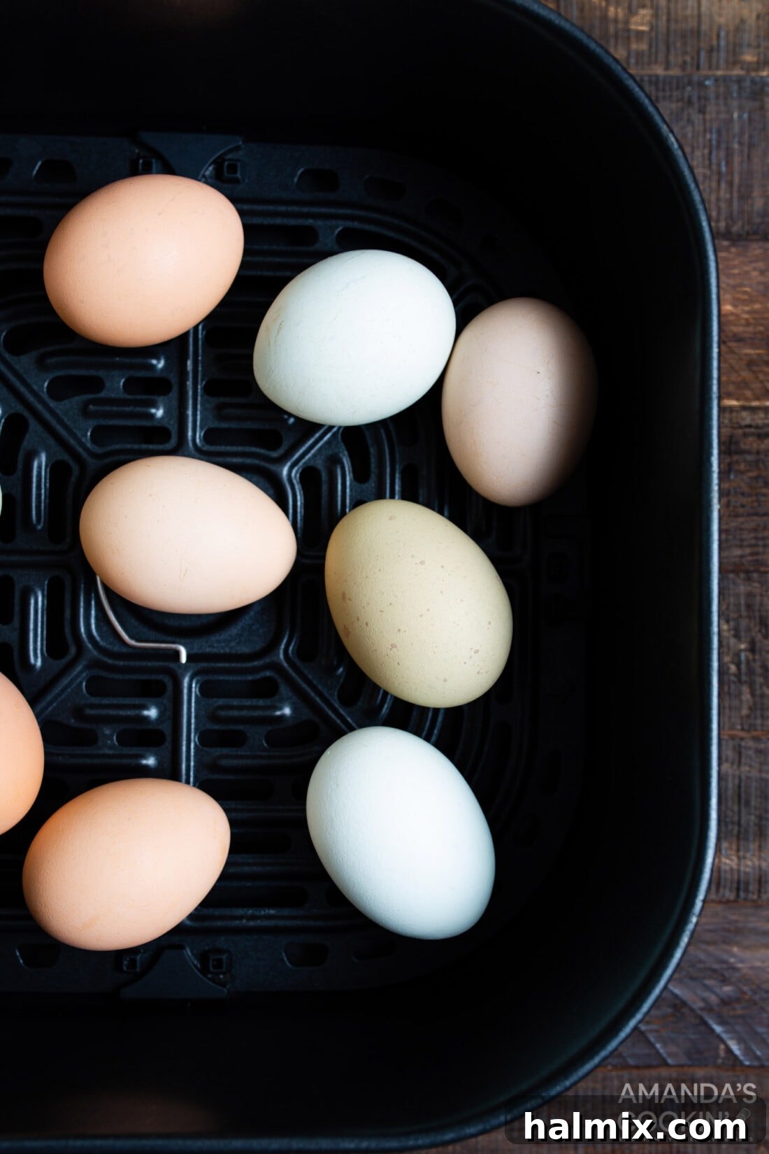 whole eggs placed in an air fryer basket before cooking