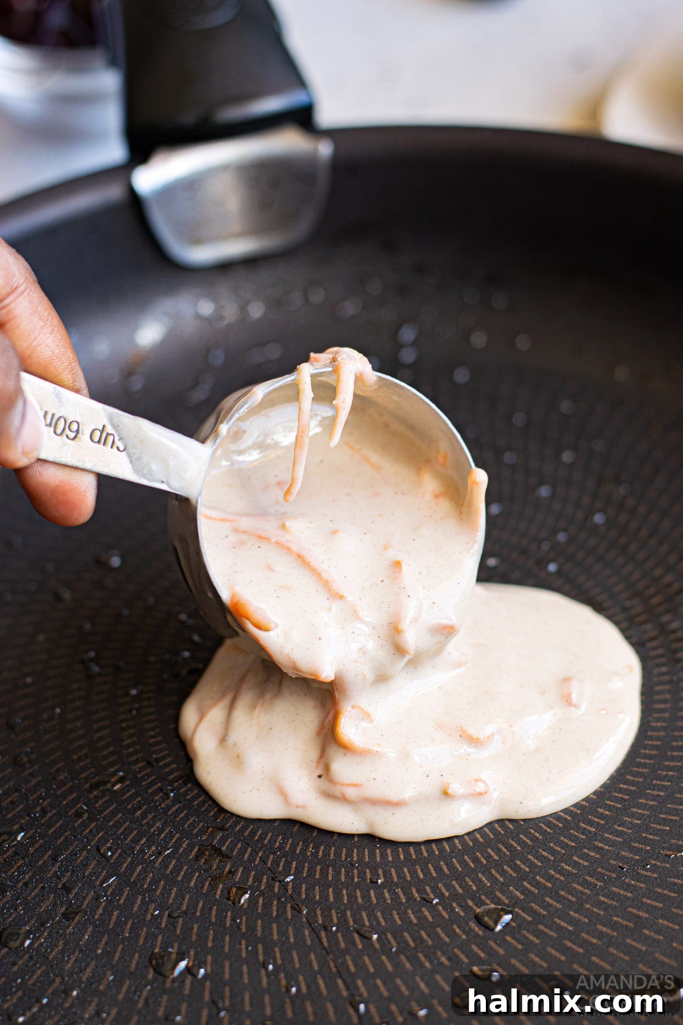 pouring carrot cake pancake batter into a skillet