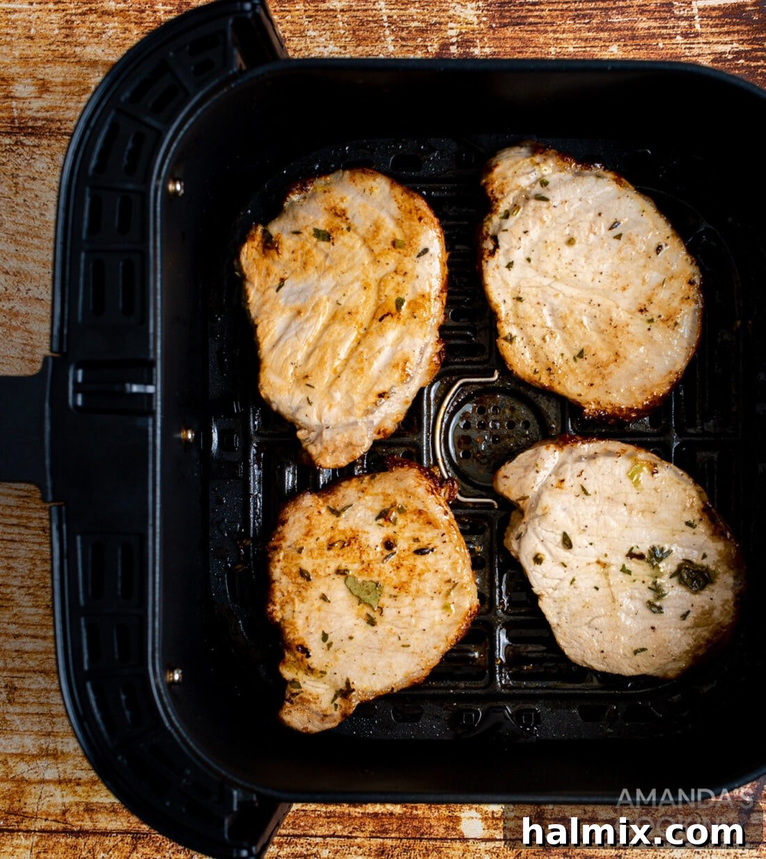Marinated pork chops placed in an air fryer basket, ready for cooking