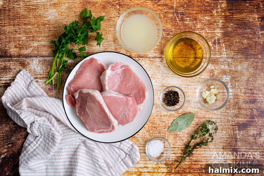 A selection of fresh ingredients including pork chops, lemon, garlic, herbs, and olive oil for the air fryer recipe