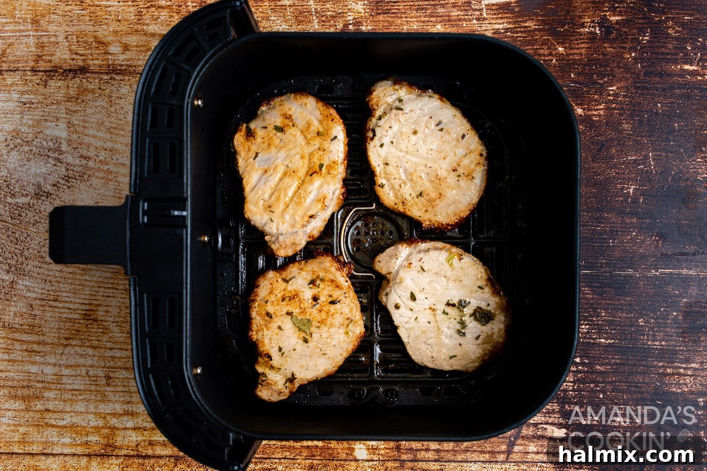 Finished pork chops removed from the air fryer, resting on a cutting board