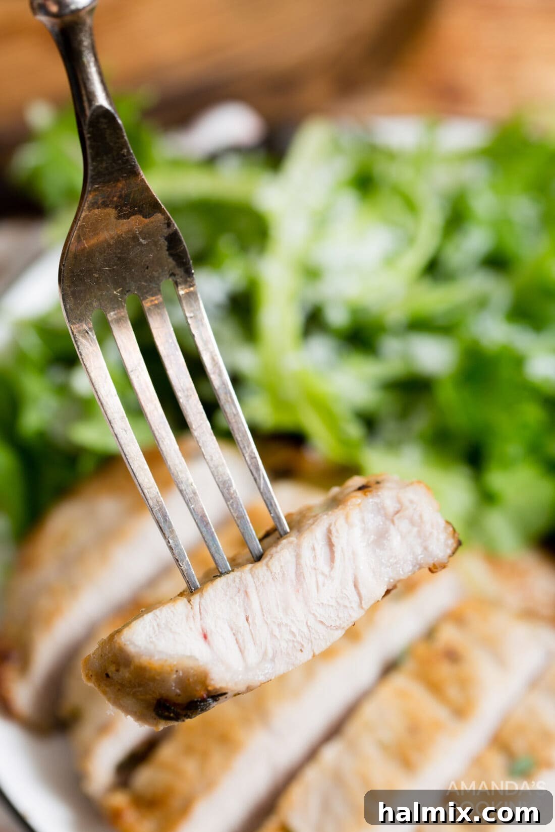 A perfectly cooked, sliced pork chop on a fork, showing its juicy interior
