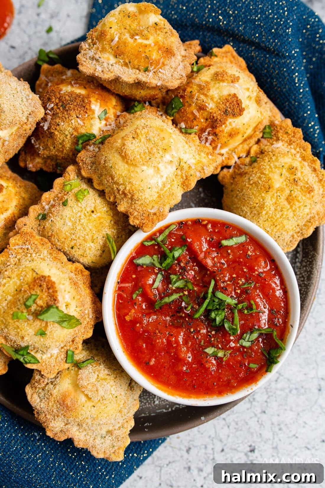 Crispy Golden Air Fryer Ravioli 2 Crispy air fryer ravioli served on a white plate with a side of marinara dipping sauce.