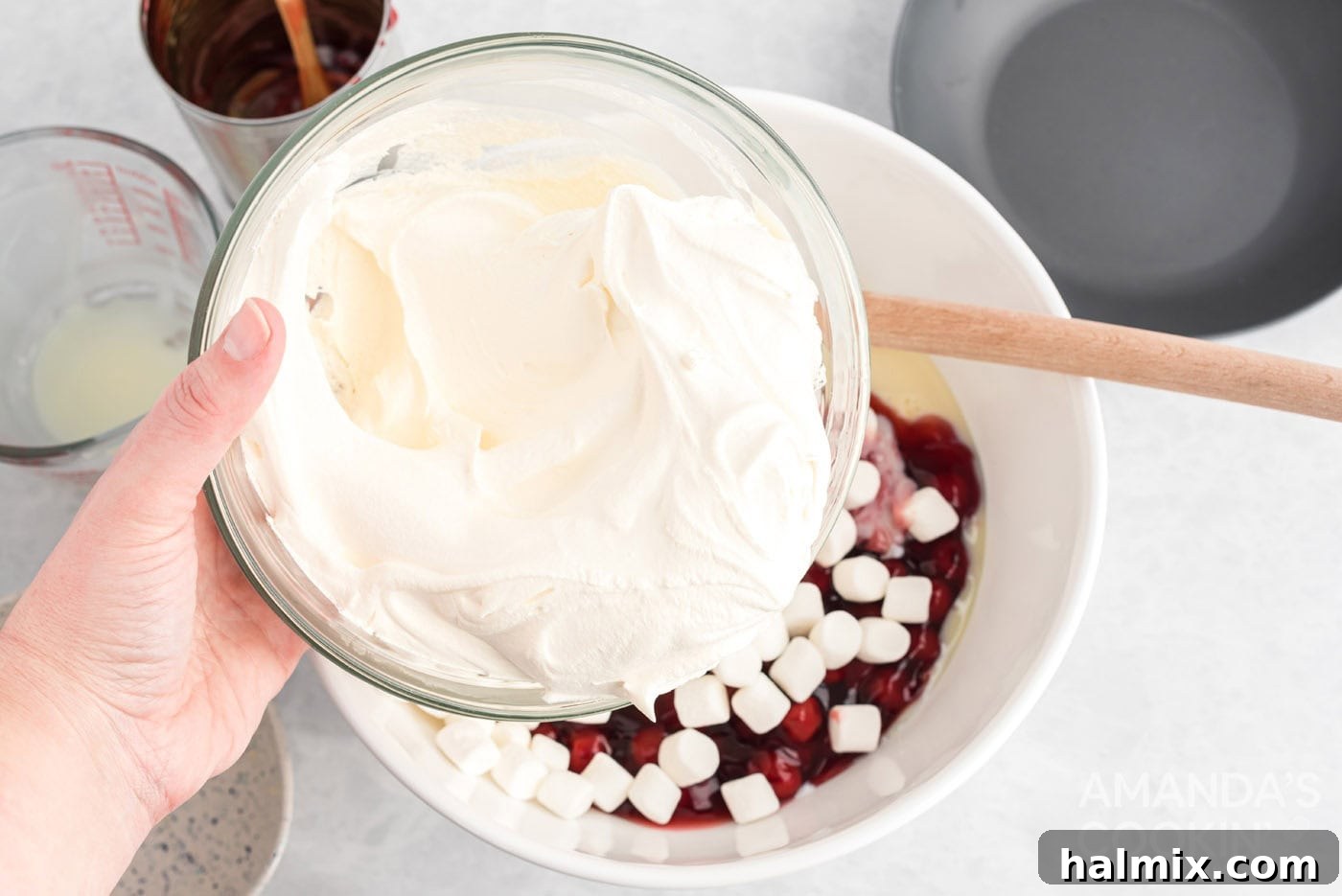 Ruby Cloud Delight 5 Adding cool whip to other ingredients in a bowl for cherry fluff.