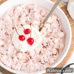 Ruby Cloud Delight 8 Close up photo of a bowl of Cherry Fluff topped with cool whip and maraschino cherries