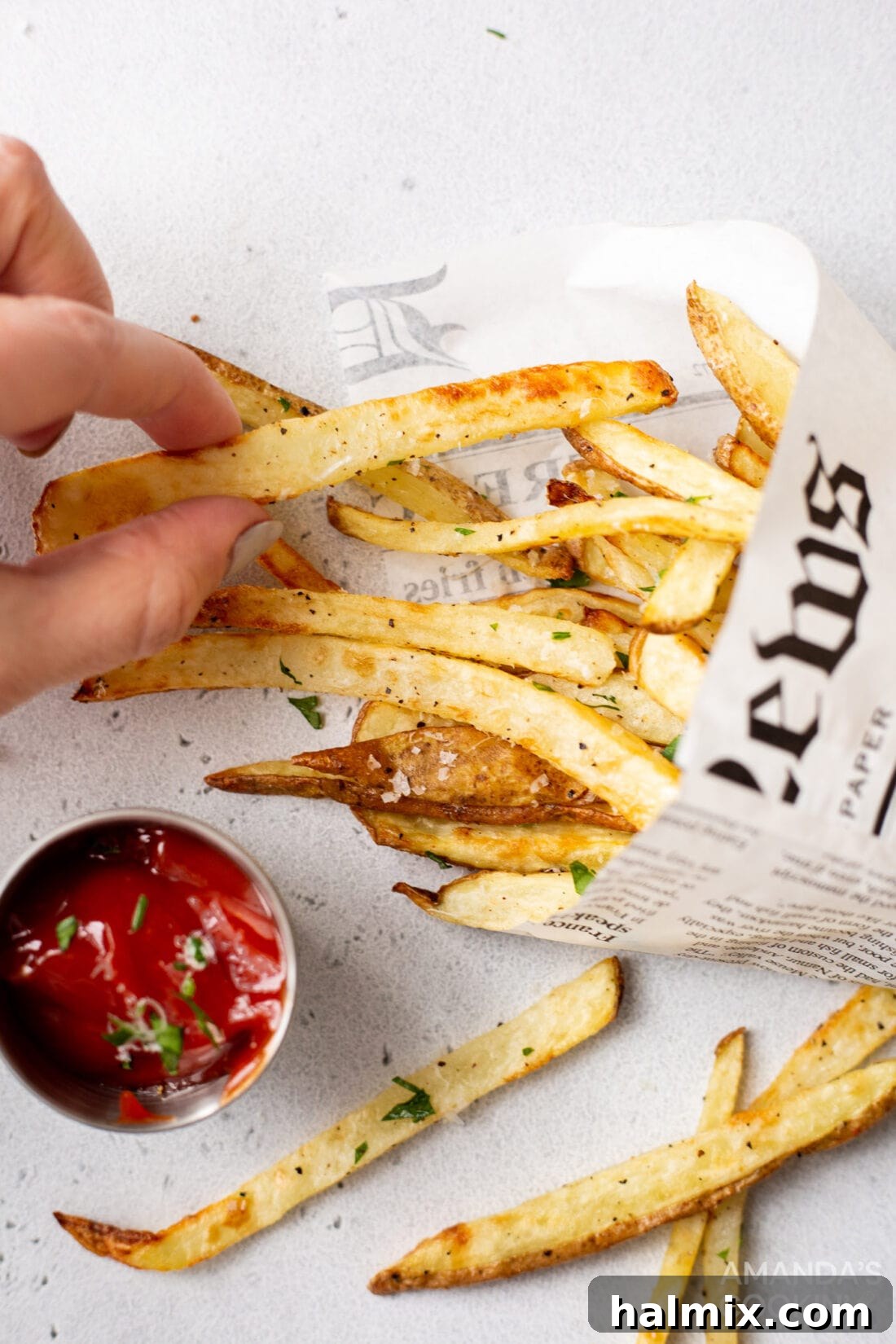 Crispy Golden Air Fryer Fries 3 A hand reaching for a perfectly golden-brown air fryer french fry from a serving bowl, highlighting its appealing crisp texture.