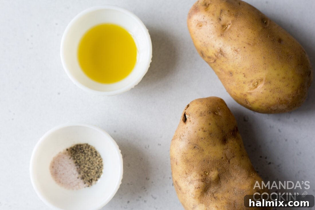 Crispy Golden Air Fryer Fries 4 A selection of ingredients for air fryer french fries, including whole Yukon gold potatoes, a bottle of olive oil, salt, and pepper, neatly arranged on a counter.