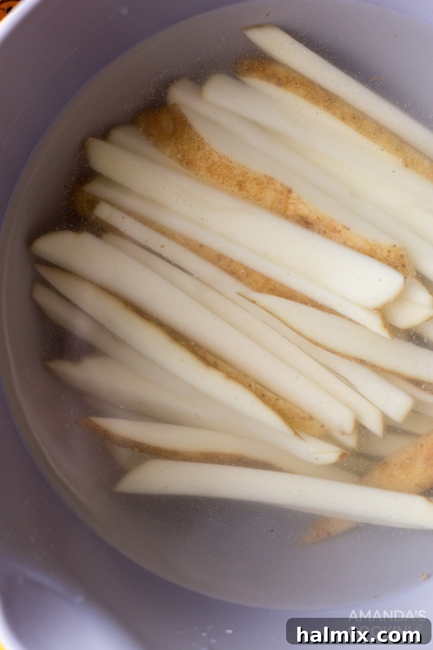 Crispy Golden Air Fryer Fries 5 Freshly cut potato slices soaking in a large bowl of cold water, a crucial step for achieving crispy air fryer French fries.