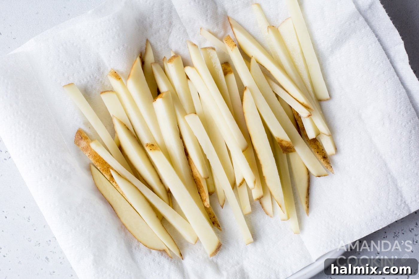 Crispy Golden Air Fryer Fries 6 Drained potato slices spread out on a paper towel, meticulously drying before being seasoned and air-fried for ultimate crispness.