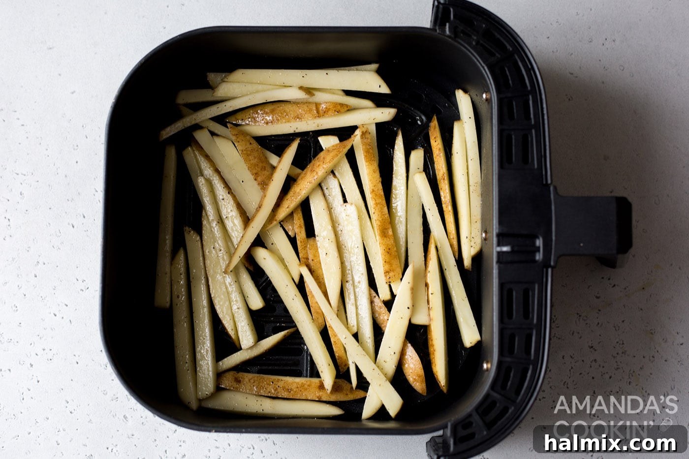 Crispy Golden Air Fryer Fries 7 Seasoned potato slices arranged in a single layer within an air fryer basket, ready for cooking.