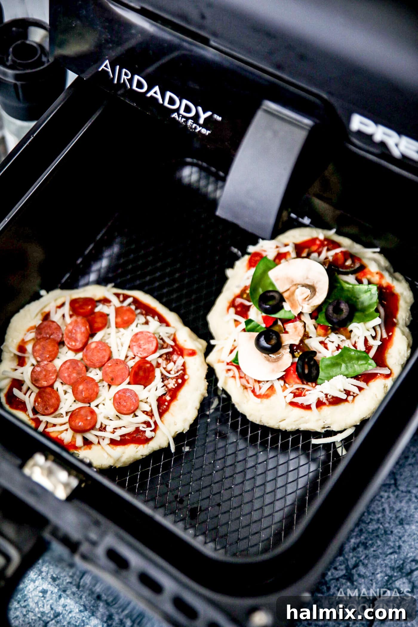 An uncooked personal pizza topped with sauce, cheese, and various ingredients, nestled within the air fryer basket before cooking.