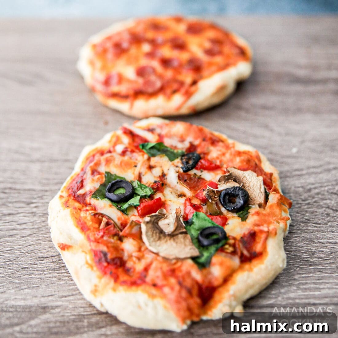 Two golden-brown air fryer personal pizzas, sliced and ready to be enjoyed, showcasing crispy crusts and melted toppings.