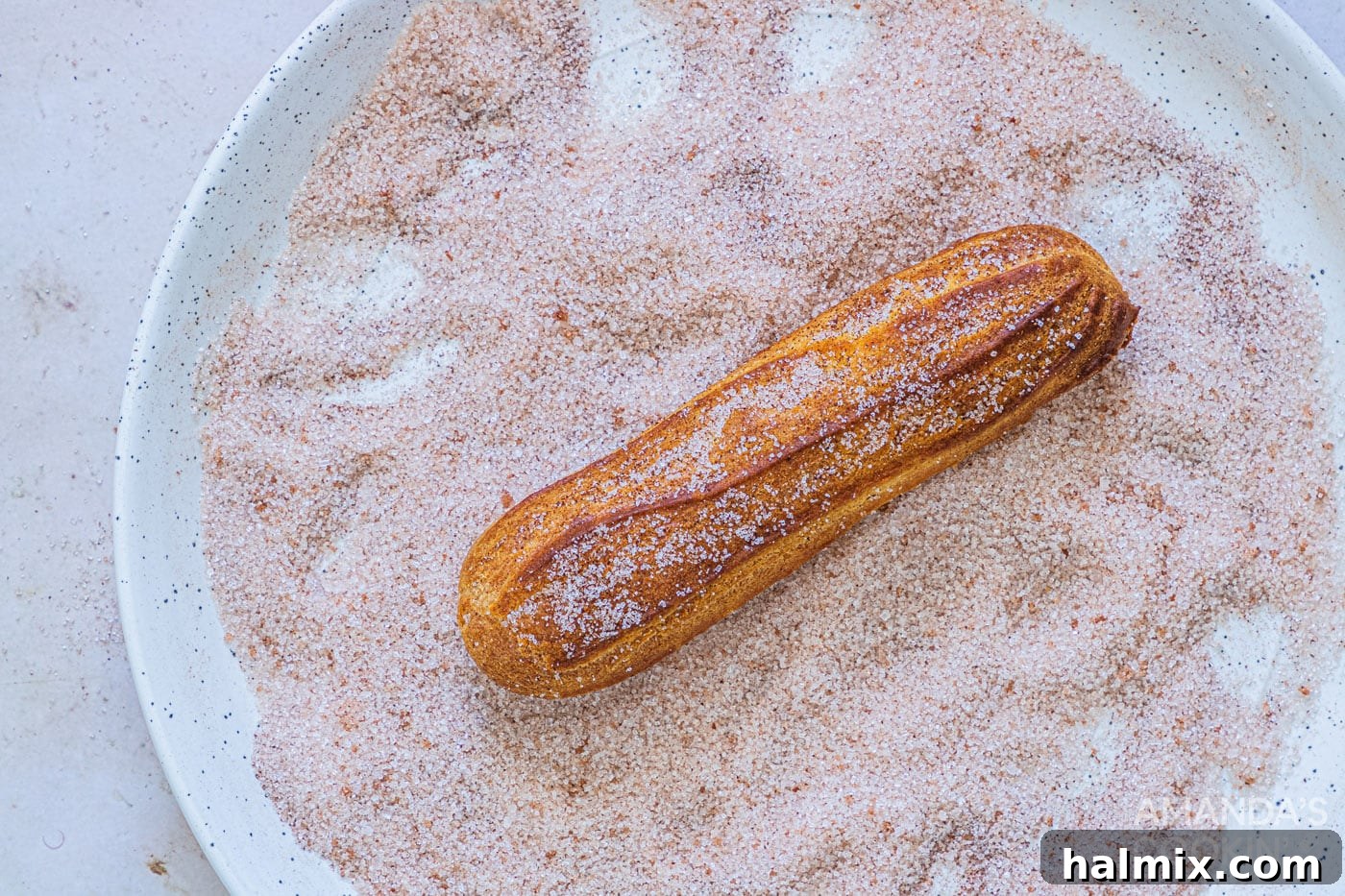 dipping churro in cinnamon sugar mixture