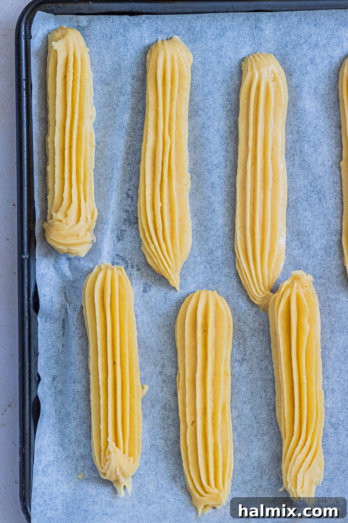 piped churro dough on a parchment lined baking sheet