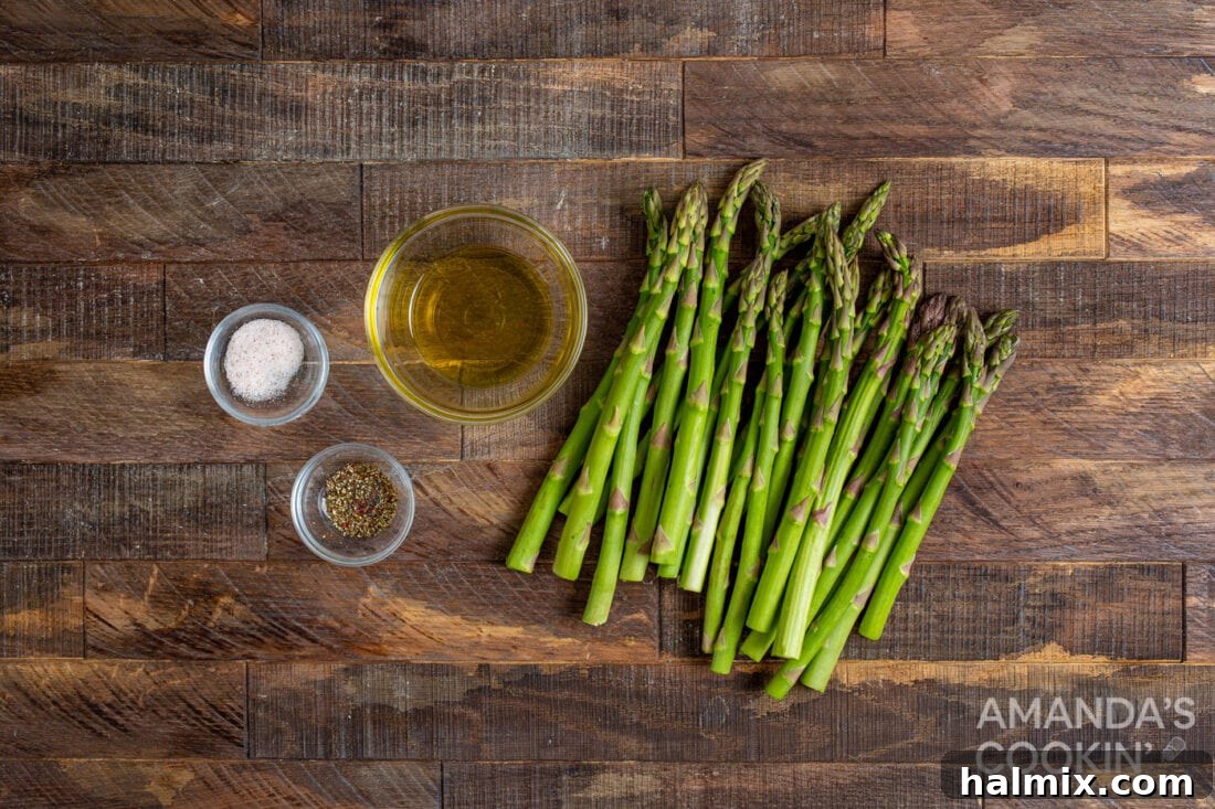 fresh asparagus, olive oil, salt, and pepper laid out as ingredients for air fryer asparagus