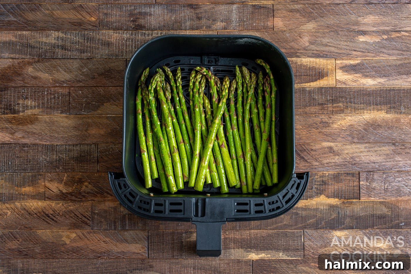 asparagus arranged in a single layer in an air fryer basket