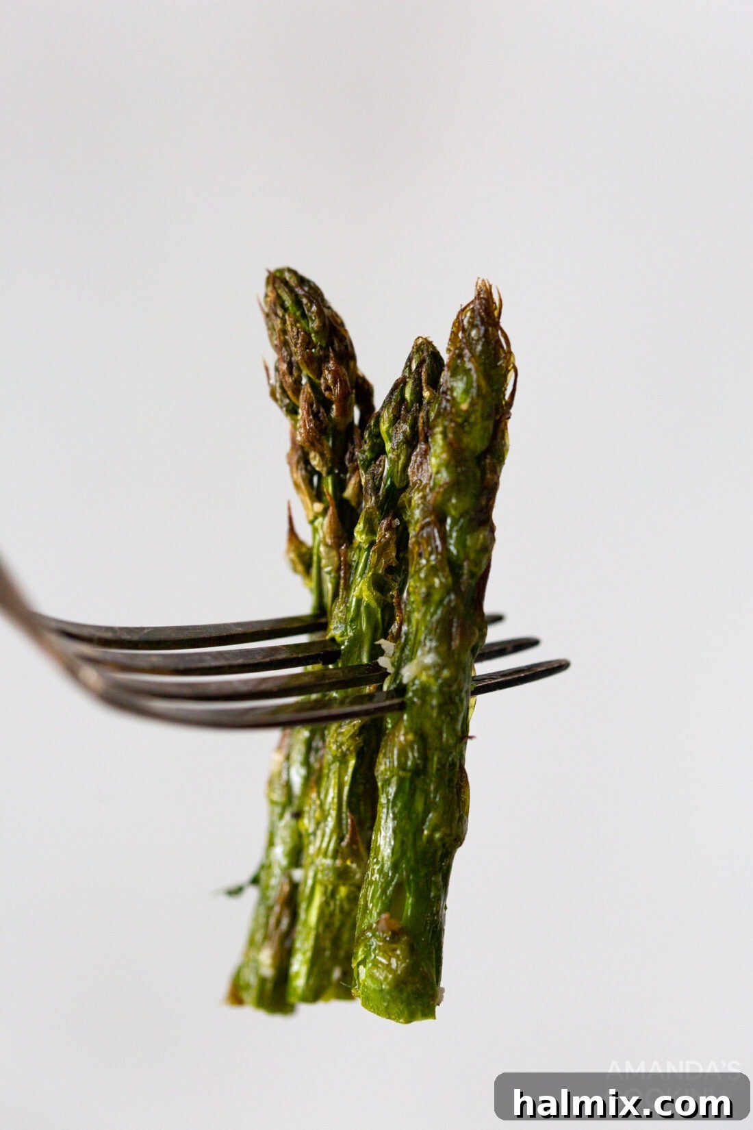 a fork lifting a piece of perfectly cooked air-fried asparagus