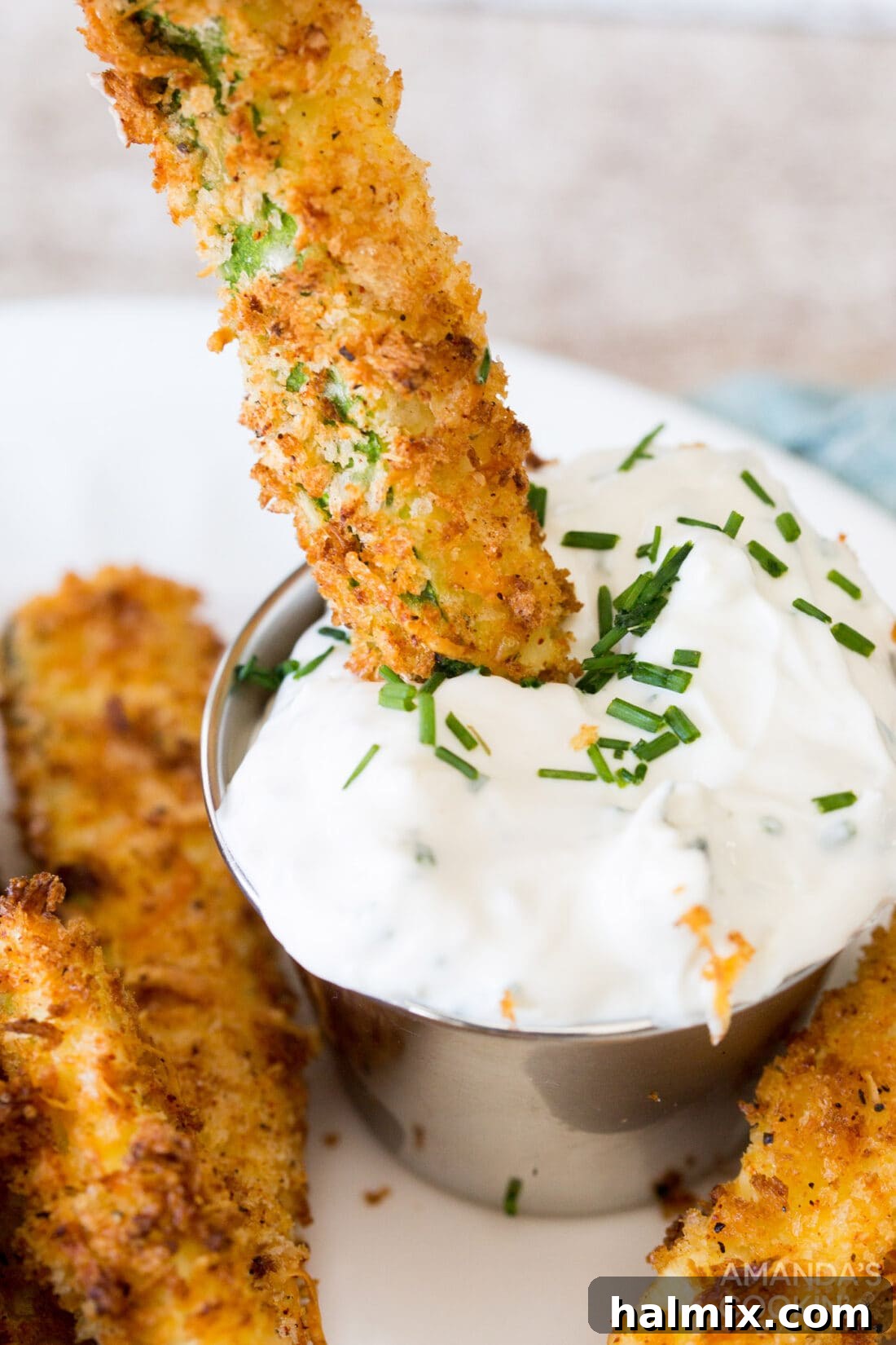 Dipping an air fryer zucchini fry into creamy sauce