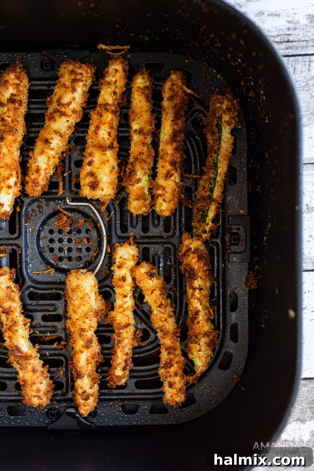 Crispy air fryer zucchini fries nestled in an air fryer basket