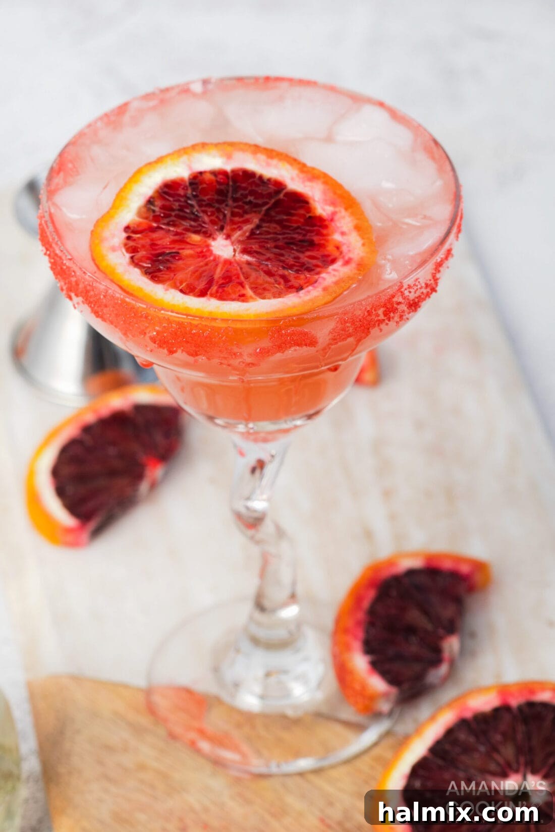 Crimson Sunset Margarita 6 Two blood orange margaritas on a table with fresh blood oranges and a shaker.