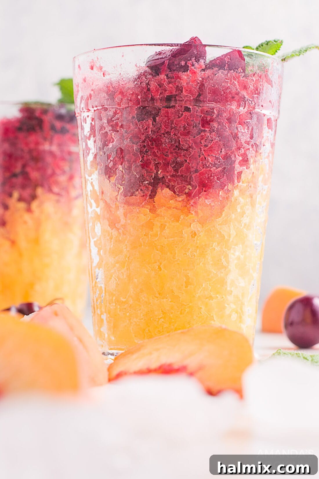 cherry and peach slushies layered in drinking glasses