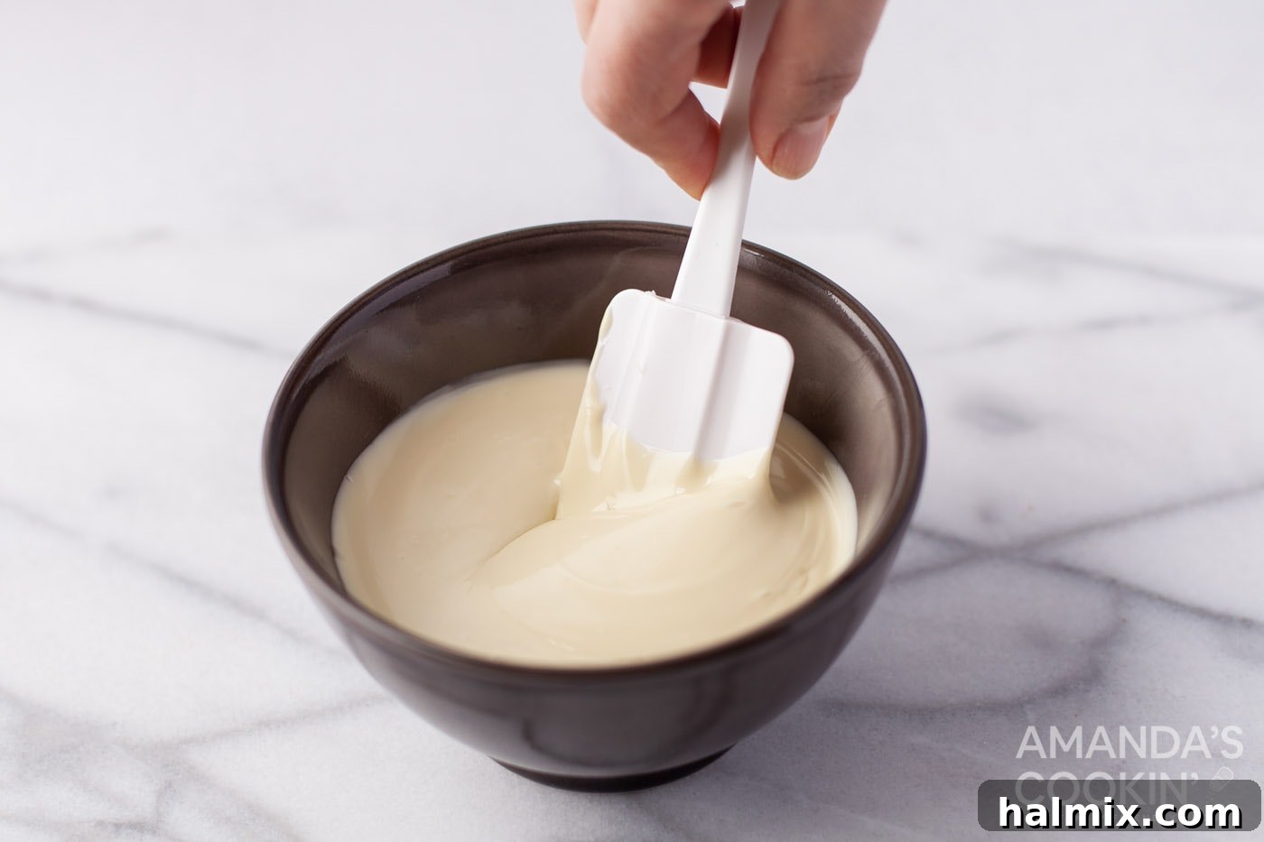 Effortless Cornflake Crunch 6 A hand stirring luxurious white chocolate in a bowl, ensuring a silky-smooth consistency.