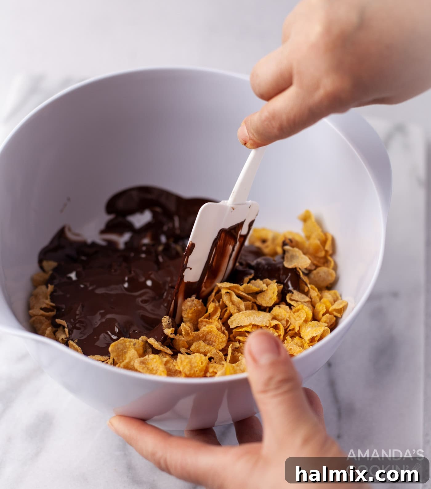 Effortless Cornflake Crunch 7 Melted chocolate generously coating crunchy cornflakes in a mixing bowl.