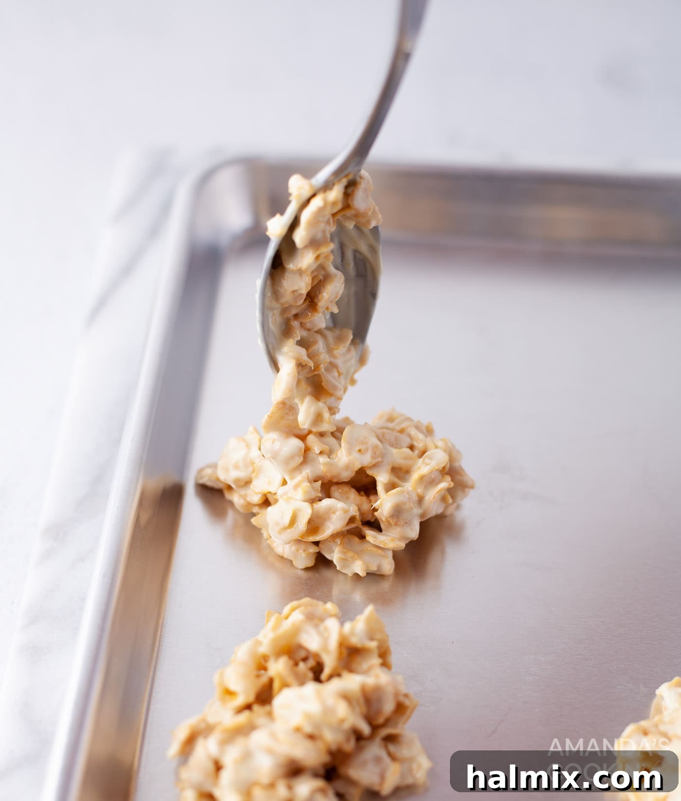 Effortless Cornflake Crunch 9 Scooping generous spoonfuls of dark chocolate cornflake mixture onto a parchment-lined baking sheet.