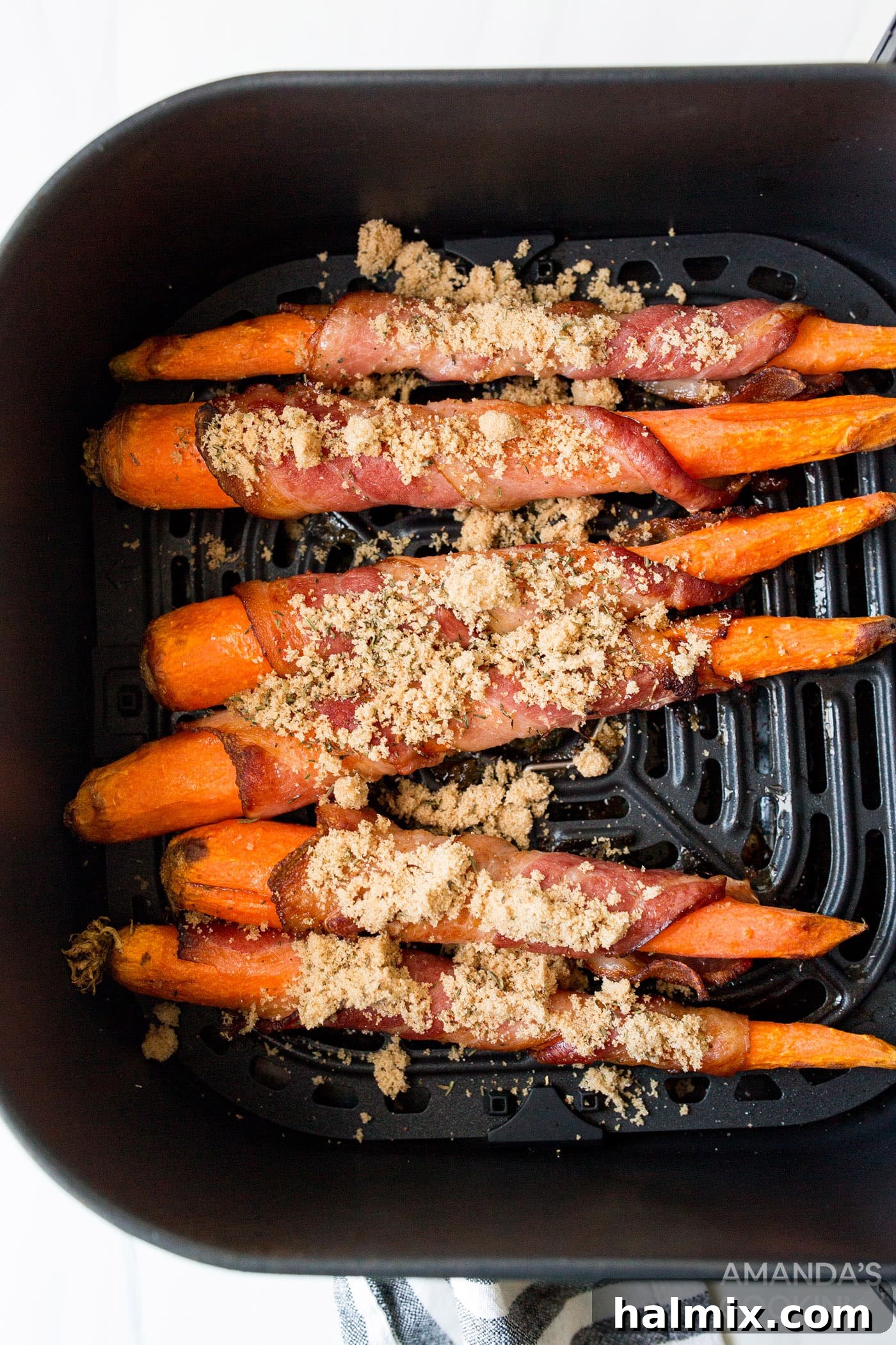 brown sugar sprinkled on bacon wrapped carrots in an air fryer
