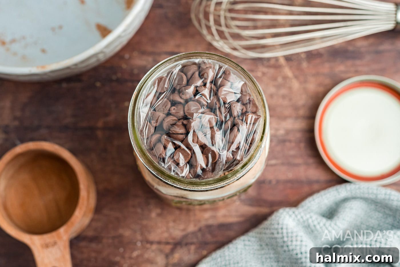 Bagged chocolate chips placed on top of the mug cake mix in a jar, ready for gifting.