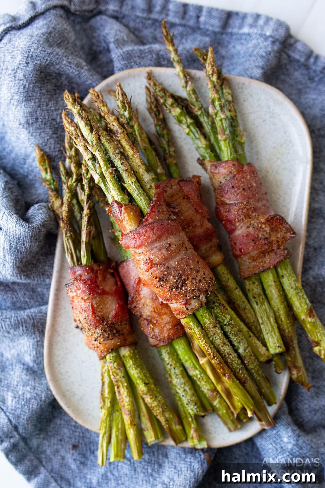 Platter of golden-brown air fryer bacon wrapped asparagus, ready to be served